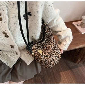 Detail of vintage leopard print bucket bag with black rope strap and golden charm pendant