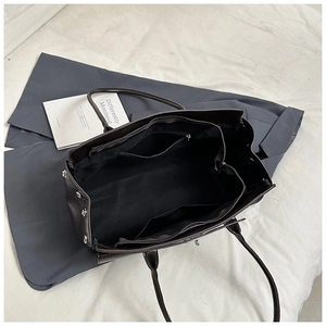 Detail view showing spacious interior with dual zip pockets and silver studs of the tote