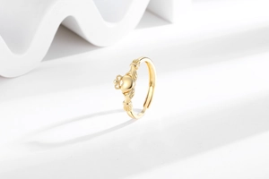Detailed view of a gold Claddagh ring featuring hands holding a heart with a crown