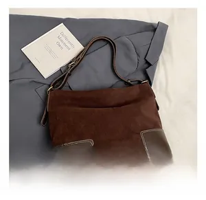 Dettaglio della borsa tote in pelle scamosciata marrone con toppe e fibbie in bronzo