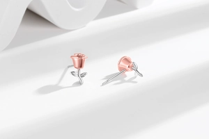 Detailed close-up of two-tone rose flower stud earrings in rose gold and silver finish