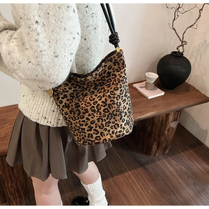 Vintage leopard print bucket bag with black strap shown on a model for a chic look