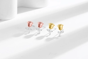 Detailed macro view of 3D rose stud earrings in gold and silver plating