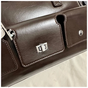 Macro detail of dark brown glossy leather shoulder bag with silver turn-lock and key charm