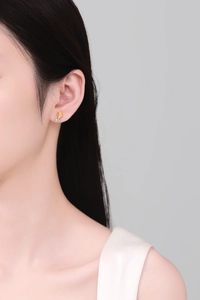 Close-up of gold rose stud earrings with silver stem on female model's ear