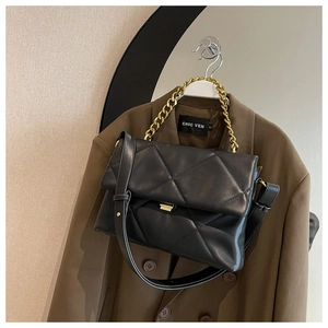 Detail of black quilted leather shoulder bag featuring gold chain and sleek metallic lock