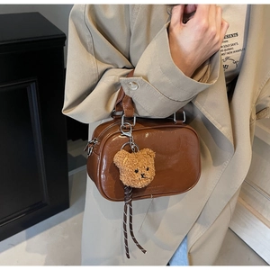 Detailed shot of a vintage brown leather bag with a cute bear charm and silver hardware