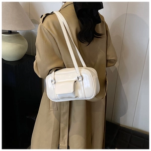 Close-up of a white patent leather shoulder bag styled with a stylish camel trench coat