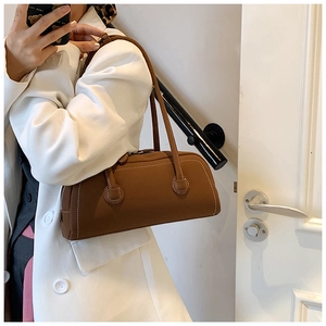 Detail view of brown leather tote bag with white contrast stitching and slim shoulder straps