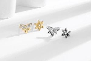 Detail of bee and flower stud earrings with pavé crystals in gold and silver finish