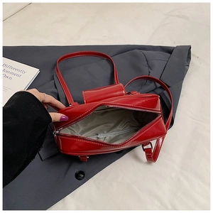 Detailed interior of red patent leather handbag featuring grey lining and zippered pocket