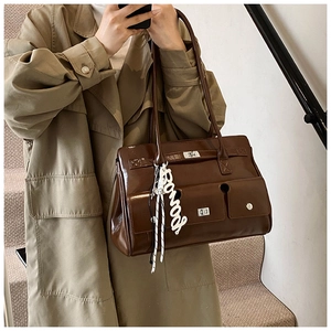 Close-up of dark brown glossy multi-pocket shoulder bag with silver locks and charms