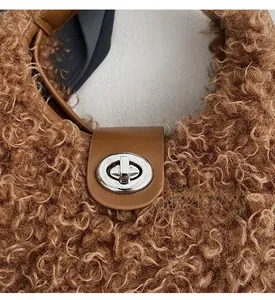Detail of silver metal turn-lock and leather trim on brown plush teddy shoulder bag