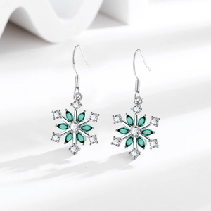 Elegant snowflake drop earrings with green zircons and silver metal on a clean studio display