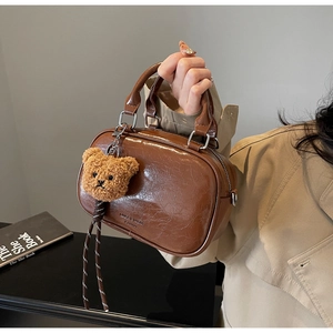 Detail of vintage brown patent leather handbag with cute plush bear charm and metallic zipper
