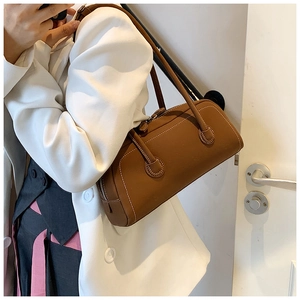 Detail of caramel tote bag showing white contrast stitching and matte leather texture