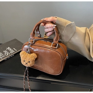 Detailed close-up of brown vintage leather bag texture with cute bear plush charm