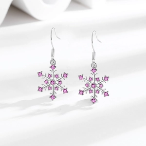 Silver snowflake earrings with pink cubic zirconia stones on white textured surface