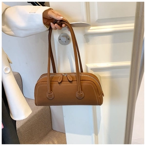 Detail of vintage brown tote bag featuring elegant white contrast stitching and zip closure