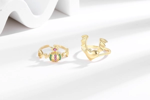 Detail view of pink heart wings and crown orb rings on minimalist white surface