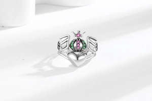 Macro detail of silver heart ring with crown, wings and colorful zircon stones