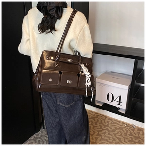 Detail of dark brown leather tote bag with glossy finish and silk scarf on strap