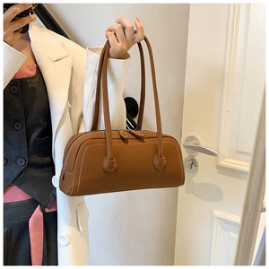 Detail of caramel leather tote bag showing white contrast stitching and shoulder straps