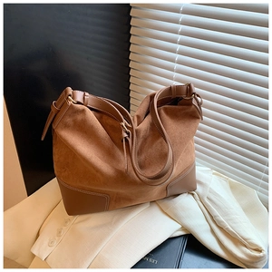 Dettaglio di camoscio caramello e cuciture in pelle liscia su una borsa a tracolla vintage