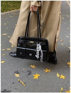 Detail of vintage black shiny shoulder bag with multi-pocket design and decorative charm
