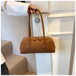 Detail view of caramel brown Boston bag featuring white contrast stitching and long straps