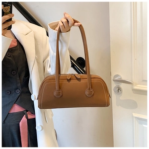 Close-up of brown pebbled leather texture and stitching on the stylish tote bag