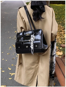 Detail of black glossy leather tote bag with multiple pockets and silver metal hardware