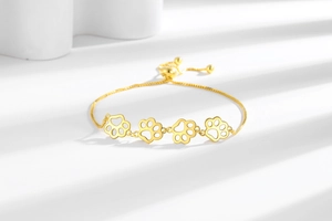 Détail du bracelet doré patte de chat avec breloques évidées et fermoir réglable coulissant