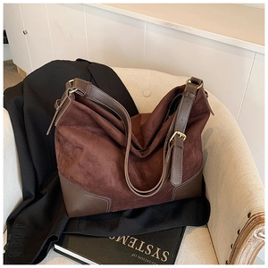 Dettaglio borsa hobo in pelle scamosciata marrone con angoli rinforzati sul divano