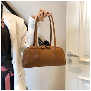 Close-up of brown tote bag featuring white contrast stitching and long double straps