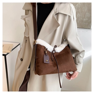 Détail d'un sac bandoulière en daim marron avec bordure en fourrure blanche et lanière