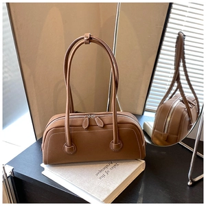 Detail of brown tote bag featuring white contrast stitching and silver zipper hardware