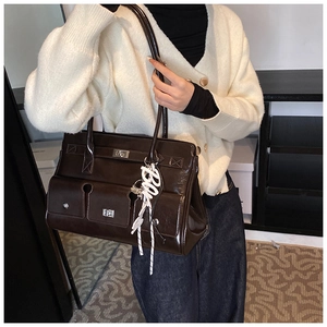 Detail of vintage brown patent leather shoulder bag with multiple pockets and metal hardware