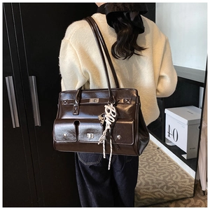 Detail of dark brown glossy patent leather satchel with silver locks and rope charm