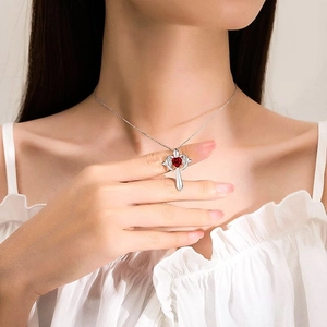 Collier croix ailes d'ange en argent avec pierre rouge en cœur sur mannequin