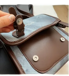 Dettaglio della chiusura magnetica argento sulla borsa in ecopelle marrone e denim