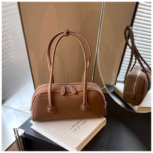 Detail view of brown leather tote bag showing white contrast stitching and dual zippers