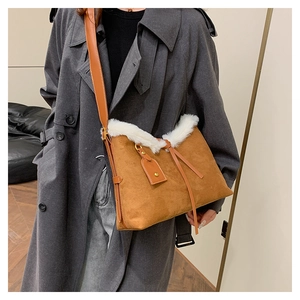 Détail d'un sac bandoulière en daim marron avec bordure en fausse fourrure blanche