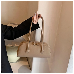 Detail showing the long slim handles and secure circular leather patches on a beige tote