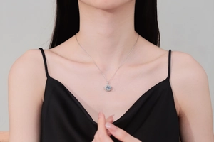 Close-up of silver Saturn pendant necklace with light blue stone on model neck