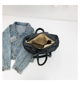 Interior view of black quilted tote bag with beige lining and functional zipper pocket