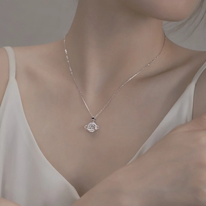Detailed view of silver planet pendant necklace with zircon inlay and black star charm