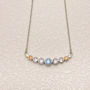 Close-up of a silver arc pendant necklace featuring nine colorful gradient zircon stones