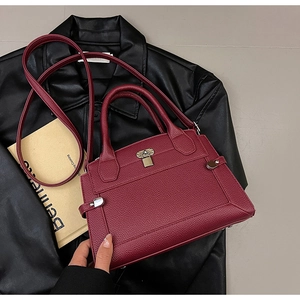 Détail de la texture cuir grainé bordeaux et boucle métallique sur le sac à main