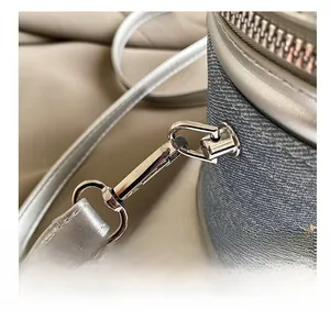 Détail du crochet argenté poli et broderie florale sur sac à main en jean bleu